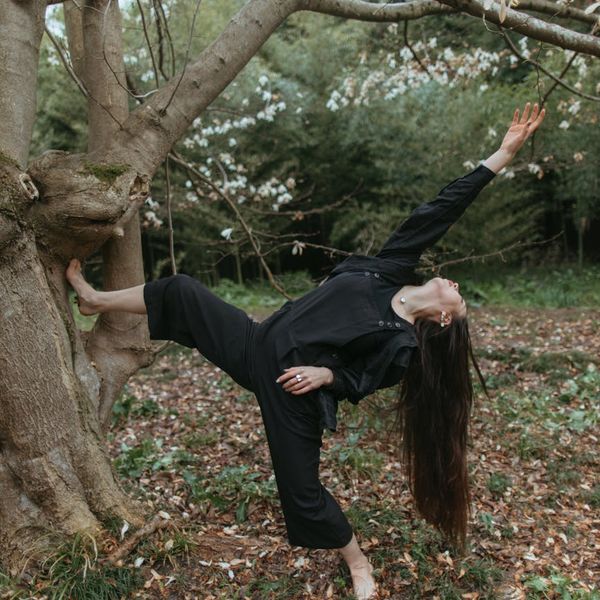Person performing a graceful balancing exercise outdoors with a serene landscape.
